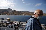 A passenger wearing a face mask to prevent the spread of the new coronavirus, stands on the deck of a ferry as it approaches the Aegean Sea island of Serifos, Greece, on Tuesday, May 26, 2020. Greece restarted regular ferry services to its islands Monday, and cafes and restaurants were also back open for business as the country accelerated efforts to salvage its tourism season. (AP Photo/Thanassis Stavrakis)