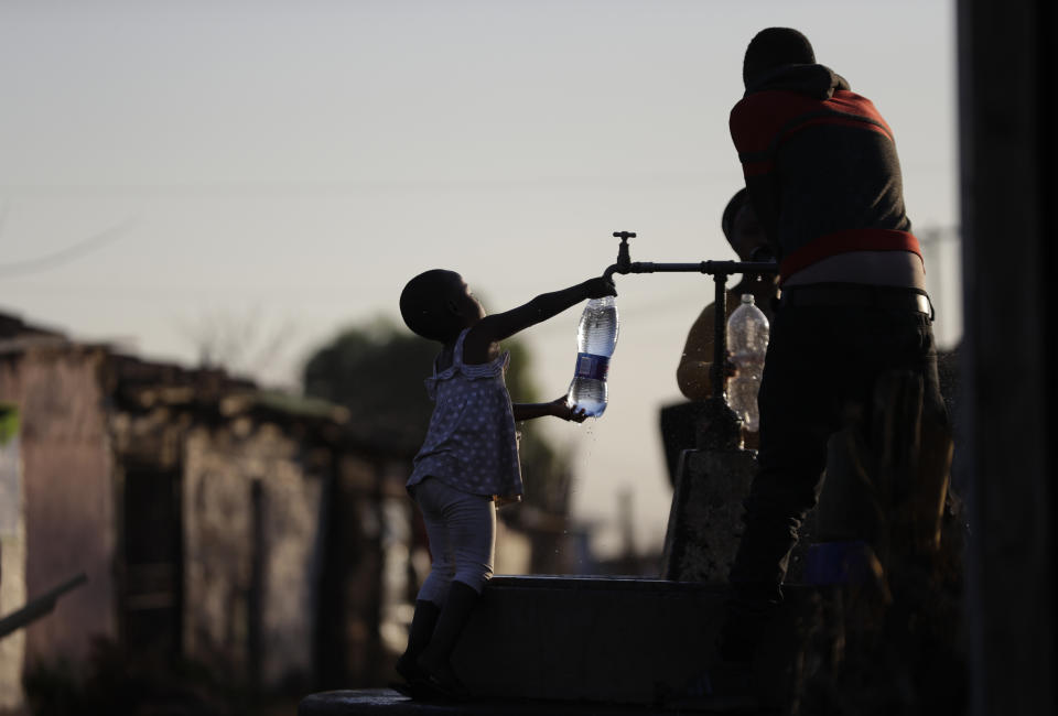 A child fills a bottle with water at a communal tap in the Katlehong Township near Johannesburg, Tuesday, Sept. 8, 2020. Official statistics show that South Africa's economy has sunk deeper into recession, with its gross domestic product for the second quarter of 2020 plummeting by 51%, largely as a result of COVID-19 and the country's strict lockdown. (APPhoto/Themba Hadebe)