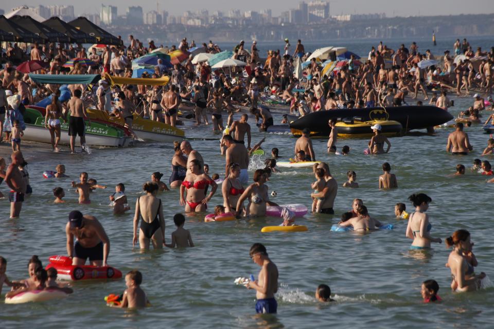 People enjoy the beach in the Black Sea in Odessa, Ukraine, Saturday, July 4, 2020. Tens of thousands of vacation-goers in Russia and Ukraine have descended on Black Sea beaches, paying little attention to safety measures despite levels of contagion still remaining high in both countries. (AP Photo/Sergei Poliakov)