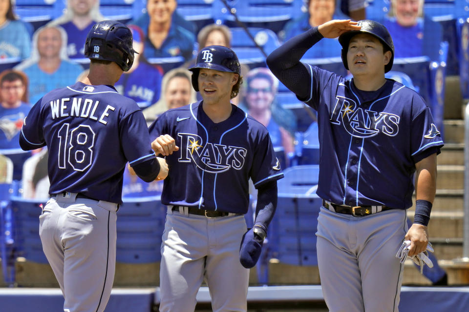Tampa Bay Rays' Joey Wendle, left, shakes hands with Taylor Walls, center, as Ji-Man Choi pretends to see how far the ball went after Wendle hit a grand slam off Toronto Blue Jays starting pitcher Trent Thornton during the first inning of a baseball game Monday, May 24, 2021, in Dunedin, Fla. (AP Photo/Chris O'Meara)
