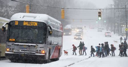 Parents lead school children past buses stopped after police closed off a stretch of Wilson Boulevard due to icy conditions in Arlington, Virginia January 6, 2015. REUTERS/Kevin Lamarque