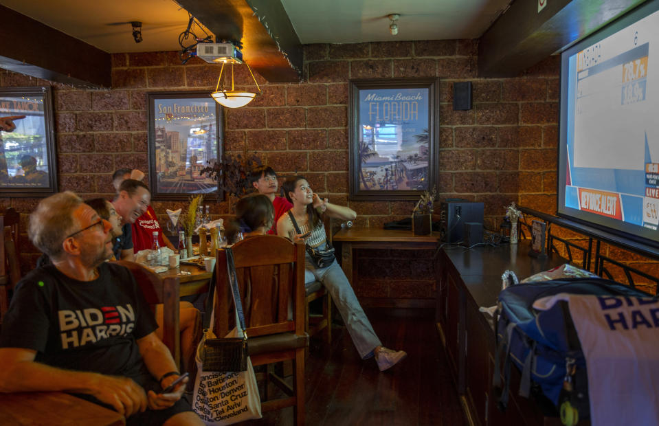 A group of U.S. Democrats supporters gather at a roadhouse restaurant to view U.S. media coverage of the U.S. presidential election in Bangkok, Thailand, Wednesday, Nov. 4, 2020. (AP Photo/Gemunu Amarasinghe)