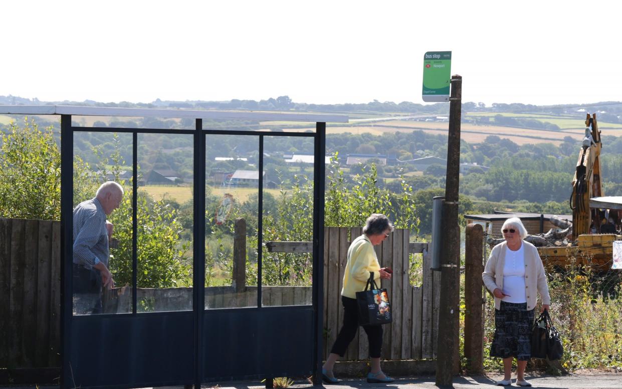 Elderly locals wait at a rural bus stop