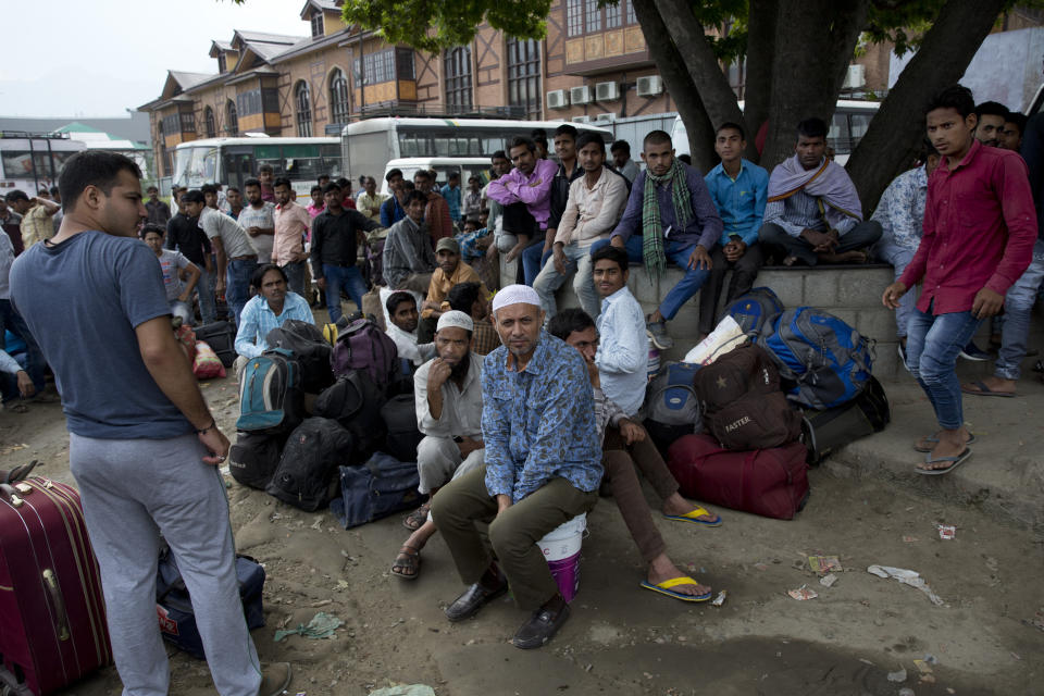 In this Tuesday, Aug. 6, 2019 photo, Indian migrant workers wait outside the government transport yard waiting to buy bus tickets to leave the region, during curfew in Srinagar, Indian controlled Kashmir. Hit by a complete security lockdown in Kashmir, hundreds of poor migrant workers have begun fleeing the Himalayan region to return to their far-away villages in northern and eastern India. (AP Photo/ Dar Yasin)