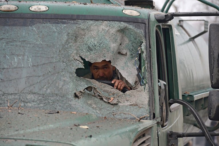 An Afghan truck driver peers through the broken windshield of his vehicle at the site of a suicide attack near the Afghan intelligence agency headquarters in Kabul on January 16, 2013. A squad of suicide bombers attacked the Afghan intelligence agency headquarters in heavily-fortified central Kabul Wednesday, killing at least one guard and wounding dozens of civilians, officials said