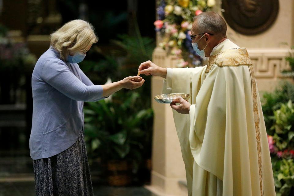 A parishioner receives communion from the Rev. Jan Schmidt during a service at St. Peter in Chains Cathedral Basilica in 2020.