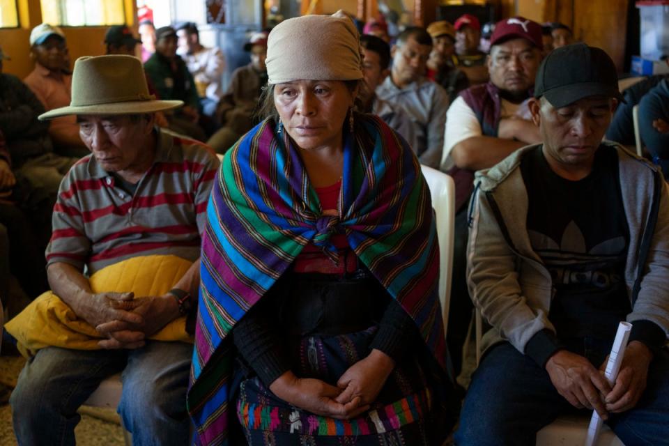 Magdalena Tepaz (cen) y Manuel de Jesus Tulul (der), padres de Wilmer Tulul, esperan el inicio de una reunión de la comunidad en Tzucubal, Guatemala (Copyright 2022 The Associated Press. Todos los derechos reservados)