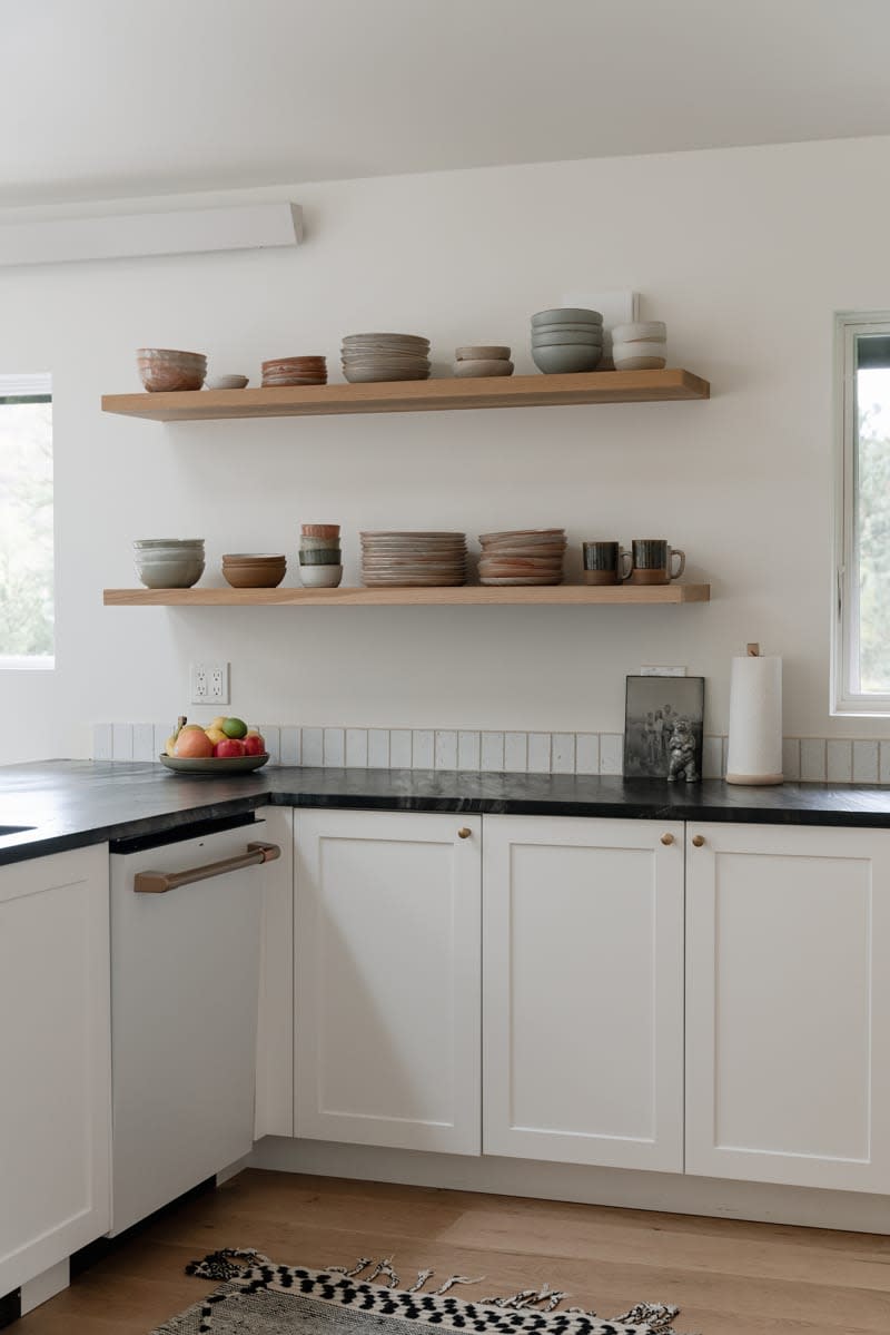 Ceramic dishware stacked on open shelves in kitchen.