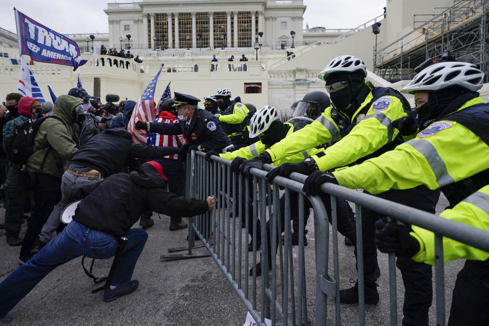 Rioters and law enforcement officers hold a fence on the West Front of the U.S. Capitol on Jan. 6, 2021, in Washington. (AP Photo/Julio Cortez)