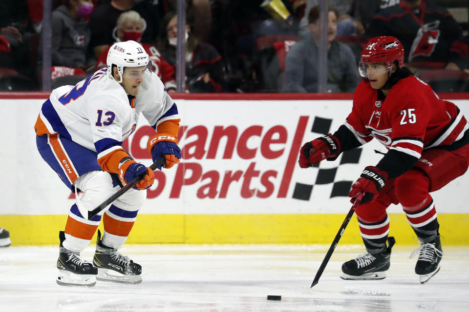 New York Islanders' Mathew Barzal (13) passes the puck past Carolina Hurricanes' Ethan Bear (25) during the second period of an NHL hockey game in Raleigh, N.C., Thursday, Oct. 14, 2021. (AP Photo/Karl B DeBlaker)