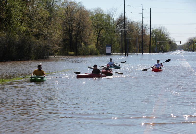 Residents paddle kayaks along a flooded street along the Tittabawassee River, after two dam failures submerged parts of Midland, Michigan