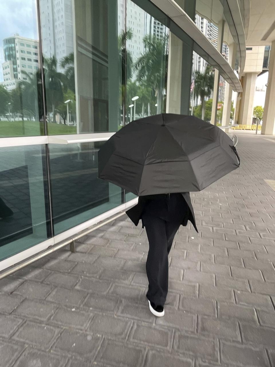 Celebrity handbag designer Nancy Gonzalez hides under an umbrella as she walks outside the federal courthouse Monday, April 22, 2024, in Miami. The Colombian designer, whose bags were purchased by celebrities like Britney Spears and the cast of the "Sex and the City" TV series, was sentenced to 18 months in federal prison on Monday for leading a smuggling ring that illegally imported into the U.S. crocodile handbags for sale at high end showrooms using couriers on commercial flights. (AP Photo/Josh Goodman)