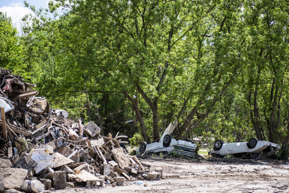 FILE - In this May 29, 2020 file photo, two cars are flipped over after major flood damage, in Sanford, Mich. Sanford village, with a population of 859, is pulling together after the devastation of two dam failures in May. Volunteers are still clearing muck and providing supplies to those whose homes were destroyed since there's no telling when major state and federal help will come.(Kaytie Boomer/The Bay City Times via AP File)