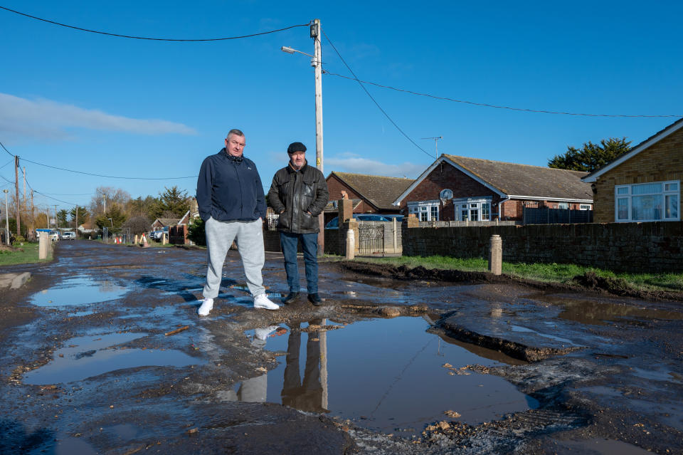 Residents stand by the large potholes. (SWNS) 