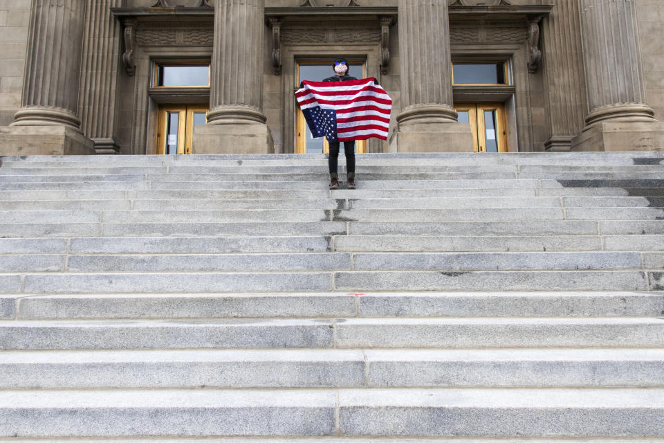 FILE - In this April 26, 2021, file photo, a student holding a U.S. flag upside down stands atop the steps at the Idaho Capitol building in Boise. The Idaho Senate has approved legislation aimed at preventing schools and universities from "indoctrinating" students through teaching critical race theory, which examines the ways in which race and racism influence American politics, culture and the law. (Darin Oswald/Idaho Statesman via AP, File)