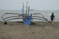 A girl walks past a boat that was placed on higher ground as they prepare for the approach of Typhoon Noru at the seaside slum district of Tondo while Typhoon Noru approaches Manila, Philippines, Sunday, Sept. 25, 2022. The powerful typhoon shifted and abruptly gained strength in an "explosive intensification" Sunday as it blew closer to the northeastern Philippines, prompting evacuations from high-risk villages and even the capital, which could be sideswiped by the storm, officials said. (AP Photo/Aaron Favila)