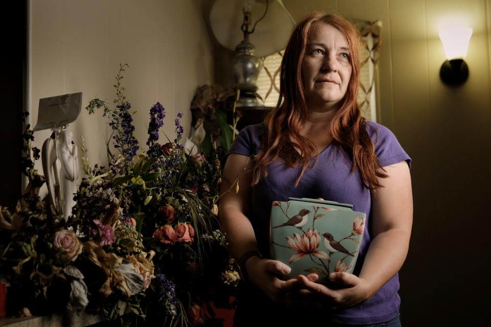 Michelle Mealey holds the urn she bought to hold her late husband's ashes as faded flowers from his funeral sit on the shelf in their her Orange Park home. Michelle's husband of 23 years, Jason Mealey, died suddenly of a heart attack several weeks ago while mowing the lawn. They were big fans of the Welcome to Rockville music festival and had plans to attend this year's event at Daytona International Speedway. Now, Michelle will be going to the festival with friends to honor his memory.