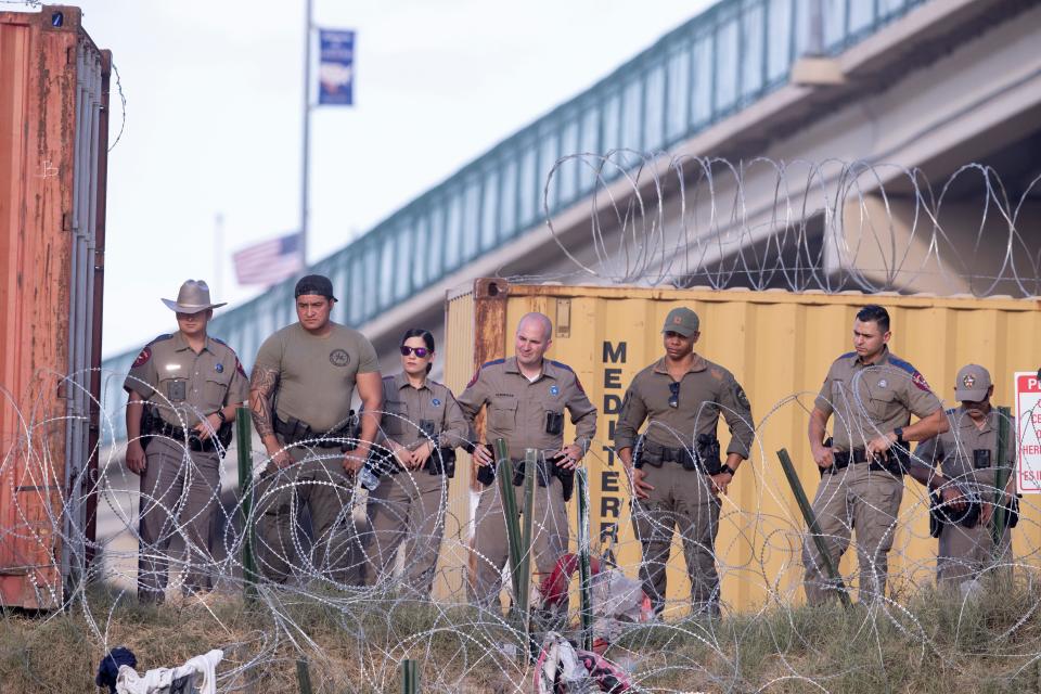 Texas Department of Public Safety officers observe as migrants struggle to walk through concertina wire in Del Rio, Texas in July.