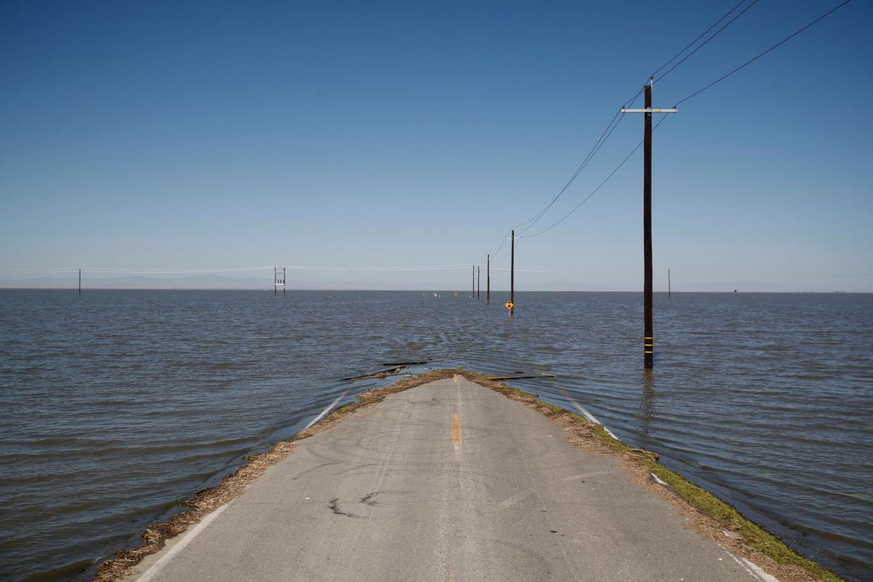 <span>Floodwaters rise in Tulare Lake basin, engulfing a road in Helm Corner, California, on 18 May 2023.</span><span>Photograph: Caroline Brehman/EPA</span>