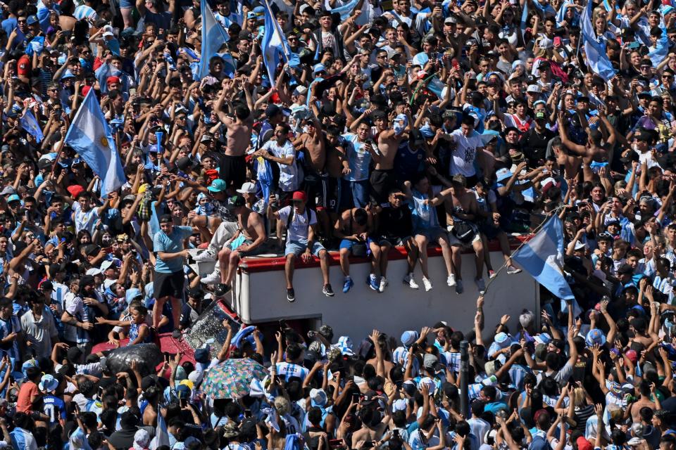 TOPSHOT - Fans of Argentina wait for the bus with Argentina's players to pass through the Obelisk to celebrate after winning the Qatar 2022 World Cup tournament in Buenos Aires on December 20, 2022. - The airplane transporting World Cup winners Argentina and their captain Lionel Messi back from Qatar arrived at the Ezeiza international airport in Buenos Aires at 2:40 am (0540 GMT) on Tuesday. On midday Tuesday they will begin a tour through the Buenos Aires city center with millions expected out in the streets on what is a public holiday. (Photo by Luis ROBAYO / AFP) (Photo by LUIS ROBAYO/AFP via Getty Images)