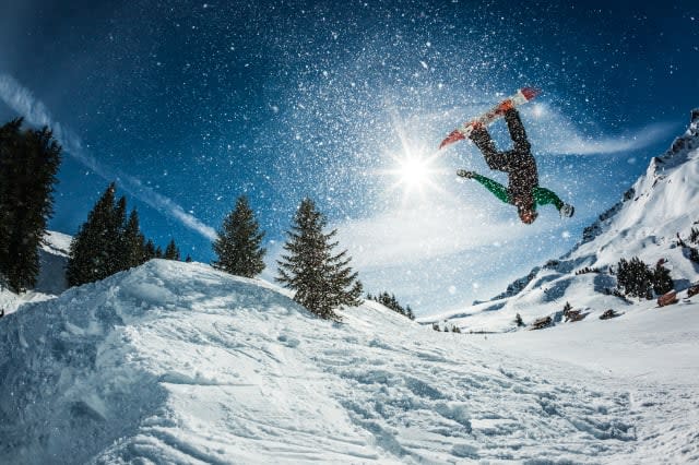 snowboarder doing a backflip with snow exploding