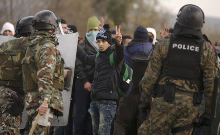 A migrant gestures in front of Macedonian police officers after trying to cross the border from Greece into Macedonia, near Gevgelija, Macedonia, November 26, 2015. REUTERS/Stoyan Nenov