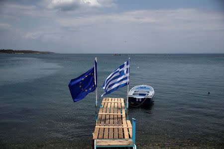 A European Union and a Greek national flag flutter on a wooden ramp on the seaside on the island of Lesbos, Greece, June 14, 2016. REUTERS/Alkis Konstantinidis