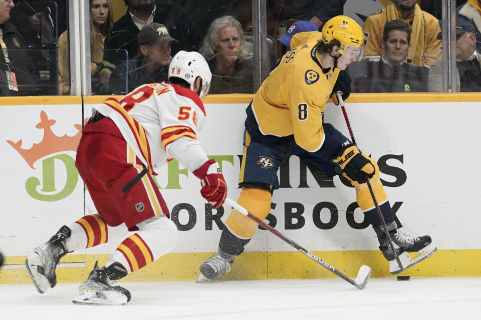 Nashville Predators' Cody Glass (8) tries to dig the puck out as Calgary Flames' Oliver Kylington (58) closes in during the second period of an NHL hockey game Tuesday, April 19, 2022, in Nashville, Tenn. (AP Photo/Mark Humphrey)