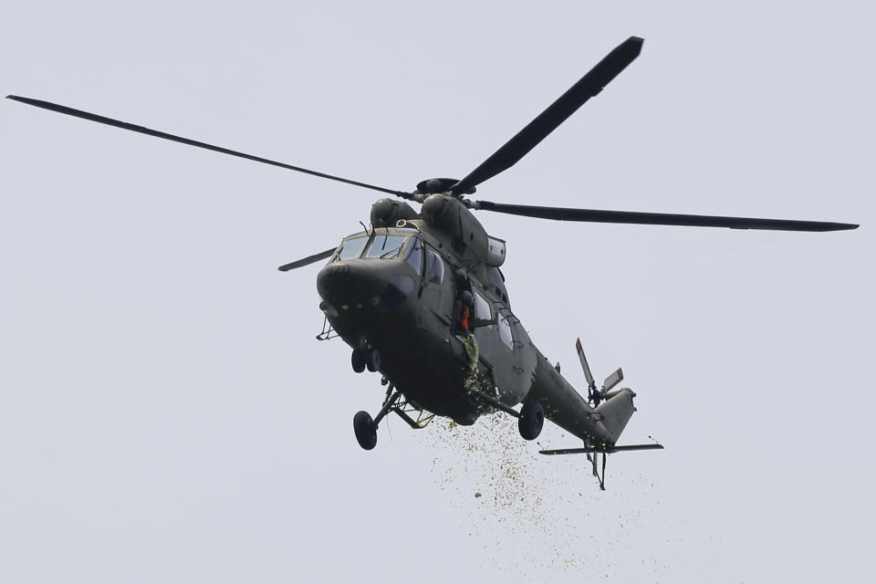 A military helicopter drops yellow confetti during the state burial rites of former Philippine President Benigno Aquino III on Saturday, June 26, 2021 at a memorial park in suburban Paranaque city, Philippines. Aquino was buried in austere state rites during the pandemic Saturday with many remembering him for standing up to China over territorial disputes, striking a peace deal with Muslim guerrillas and defending democracy in a Southeast Asian nation where his parents helped topple a dictator. He was 61. (AP Photo/Aaron Favila)