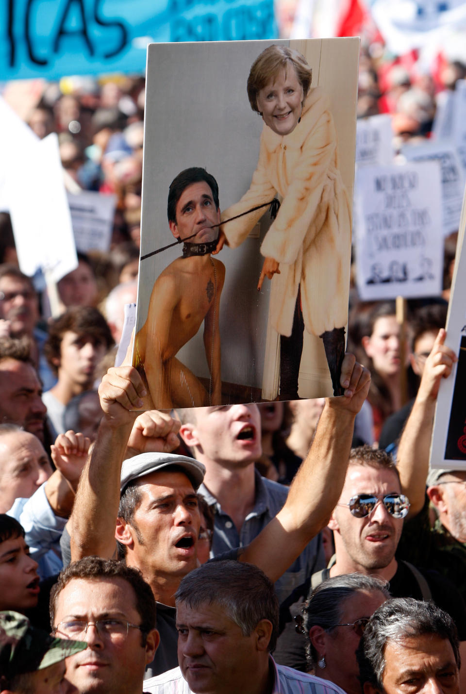 A protestor holds a collage showing German Chancellor Angela Merkel and Portuguese Prime Minister Pedro Passos Coelho during a workers unions' demonstration at Lisbon's Comercio Square, Saturday, Sept. 29 2012. Thousands of Portuguese enduring deep economic pain from austerity cuts took to the streets Saturday in protest. (AP Photo/Joao Henriques)