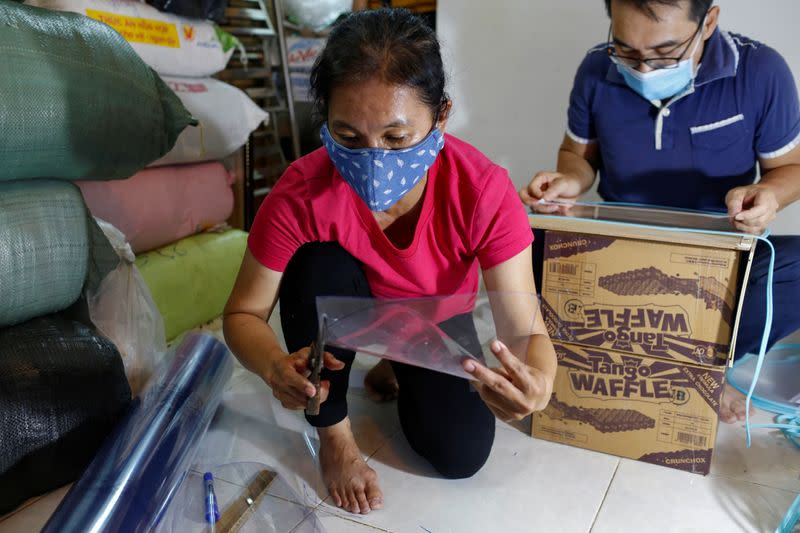 A woman is seen cutting plastic pieces to make face masks during the outbreak of the coronavirus disease (COVID-19), in Ho Chi Minh, Vietnam