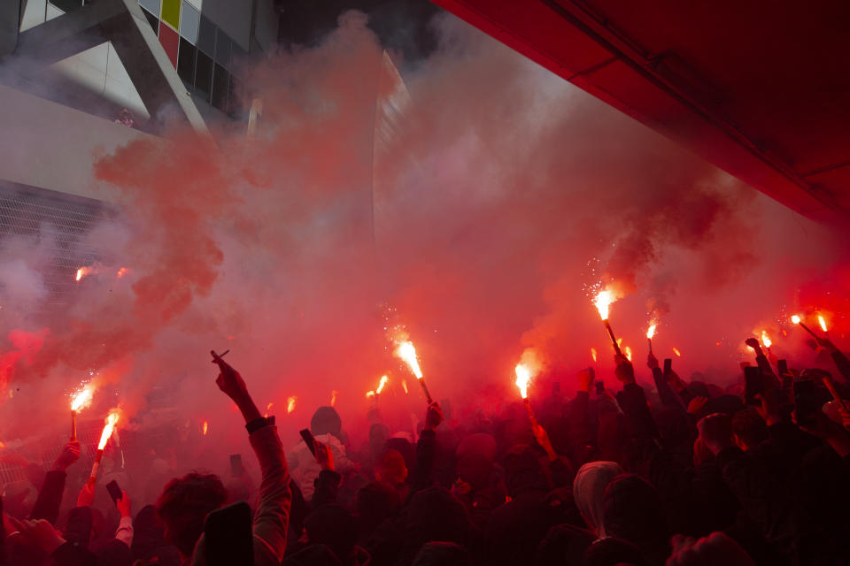 Ajax supporters set off flares as players show the trophy when clinching the Dutch Eredivisie Premier League title after winning the soccer match between Ajax and Emmen with a 4-0 score at the Johan Cruyff ArenA in Amsterdam, Netherlands, Sunday, May 2, 2021. (AP Photo/Peter Dejong)