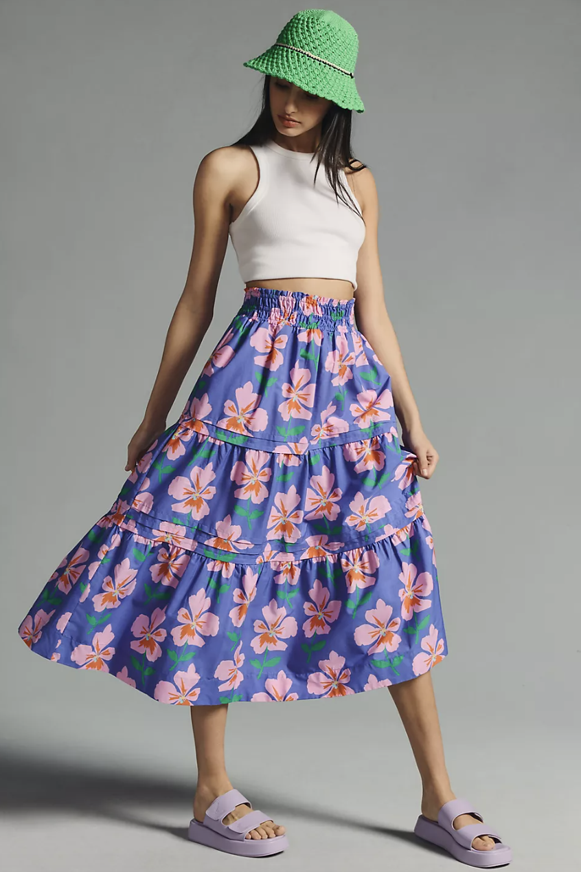 model wearing green hat, white tank top, floral The Somerset Maxi Skirt in blue motif (photo via Anthropologie)