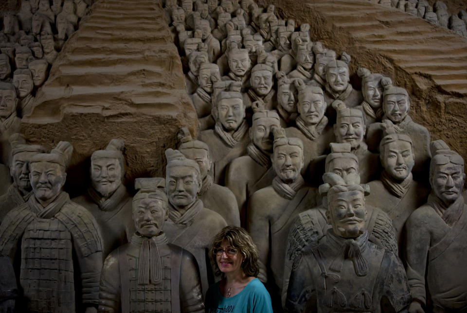 In this Tuesday, July 30, 2013 photo, a foreign tourist stands near a terracotta warrior replica as she poses for a photo at the Museum of Qin Terracotta Warriors and Horses in Xi'an, in central China's Shaanxi province. China's new tourism slogan "Beautiful China" has been criticized by industry experts who say it illustrates a marketing problem that has led to a weakness in growth in foreign visitors over the past few years. (AP Photo/Andy Wong)