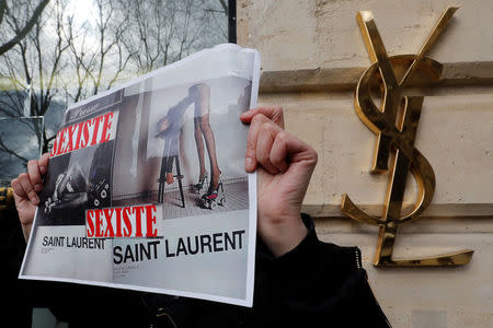 Activists hold placards which read "Sexist" during a demonstration in front of a Yves Saint Laurent shop in Paris, France, March 7, 2017. REUTERS/Philippe Wojazer