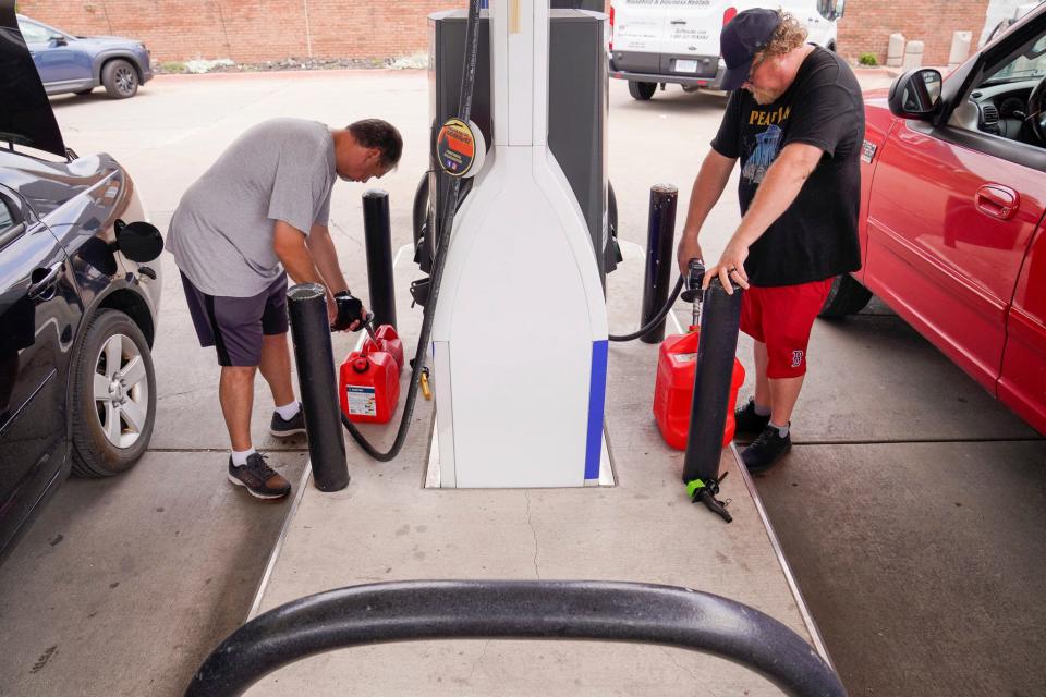 David Turner, 49, of Grosse Pointe Park, and Kevin Landon, 50, of Detroit, fill up their portable fuel containers at the Marathon gas station on the corner of Alter Road and Jefferson Avenue in Grosse Pointe Park on Thursday, July 27, 2023. They need the fuel to power their generators at home after they lost power during intense storms on Wednesday. "This is my second fill-up of the day," said Turner.