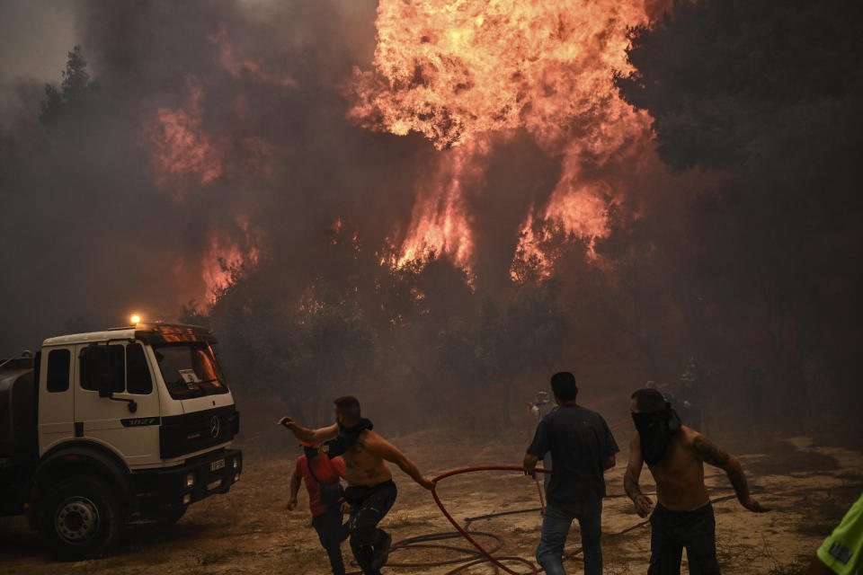 TOPSHOT - Firefighters and volunteers flee during a wildfire in Chasia in the outskirts of Athens on August 22, 2023. Greece's fire brigade on August 22, 2023 ordered the evacuation of a district on Athens' northwestern flank as firefighters battled a steadily growing wave of wildfires around the country, the second in a month. Tens of thousands of people have been urged to leave the district of Ano Liosia, while at the neighbouring community of Fyli an AFP journalist saw homes on fire. (Photo by Angelos Tzortzinis / AFP) (Photo by ANGELOS TZORTZINIS/AFP via Getty Images)