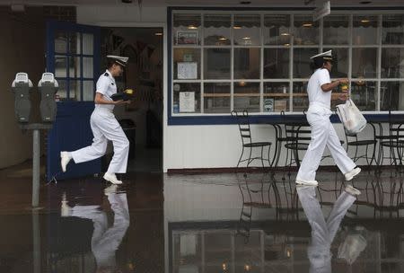 U.S. Naval Academy Midshipmen who declined to give their names, tiptoe through the water in front of "Pip's Dock Street Dogs" after the Chesapeake Bay overflowed its banks at City Dock in Annapolis, Maryland May 16, 2014. REUTERS/Mary F. Calvert