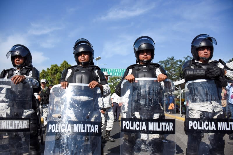 Military police guard the border between Guatemala and Mexico as migrants, part of a caravan travelling to the U.S., wait to cross in to Mexico in Ciudad Hidalgo