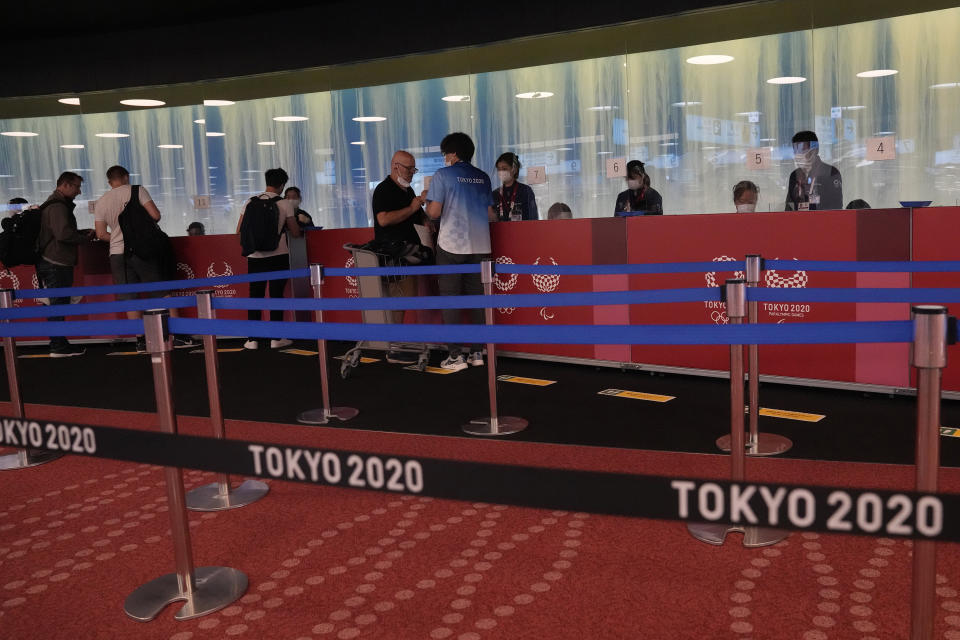 People arriving for the 2020 Summer Olympics wait for their credentials to be validated before they can leave Haneda Airport in Tokyo, Monday, July 19, 2021. (AP Photo/Natacha Pisarenko)