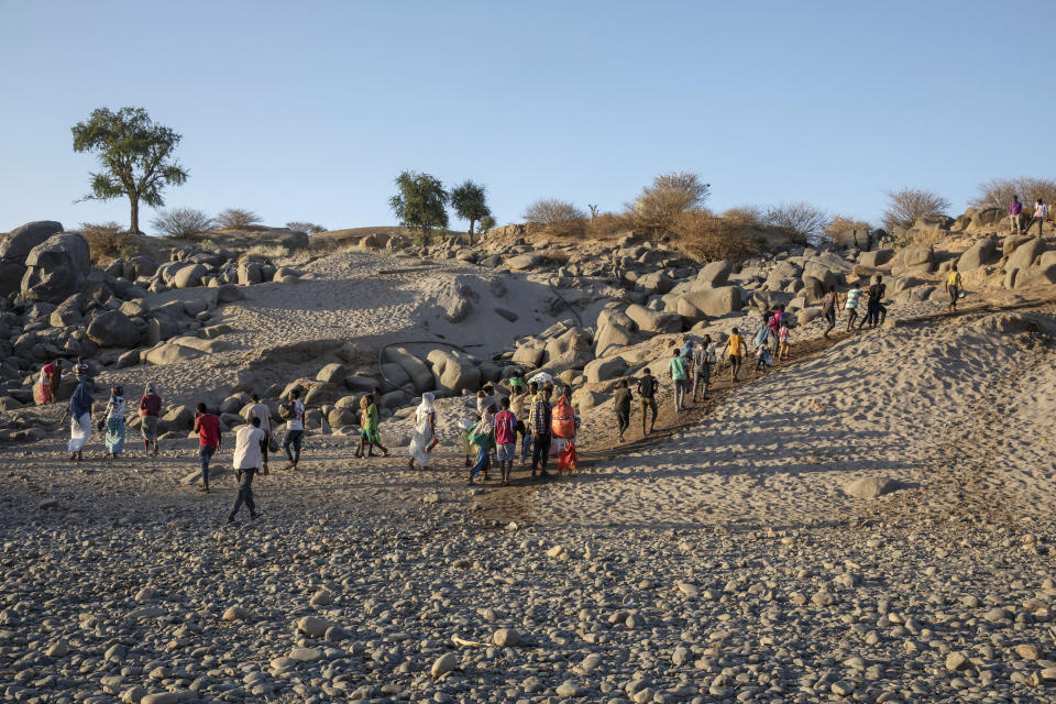 A Tigray refugees walk a hill after arriving on the banks of the Tekeze River on the Sudan-Ethiopia border, in Hamdayet, eastern Sudan, Wednesday, Dec. 2, 2020. Ethiopian forces on Thursday, Dec. 3, 2020 blocked people from the country's embattled Tigray region from crossing into Sudan at the busiest crossing point for refugees, Sudanese forces said. (AP Photo/Nariman El-Mofty)