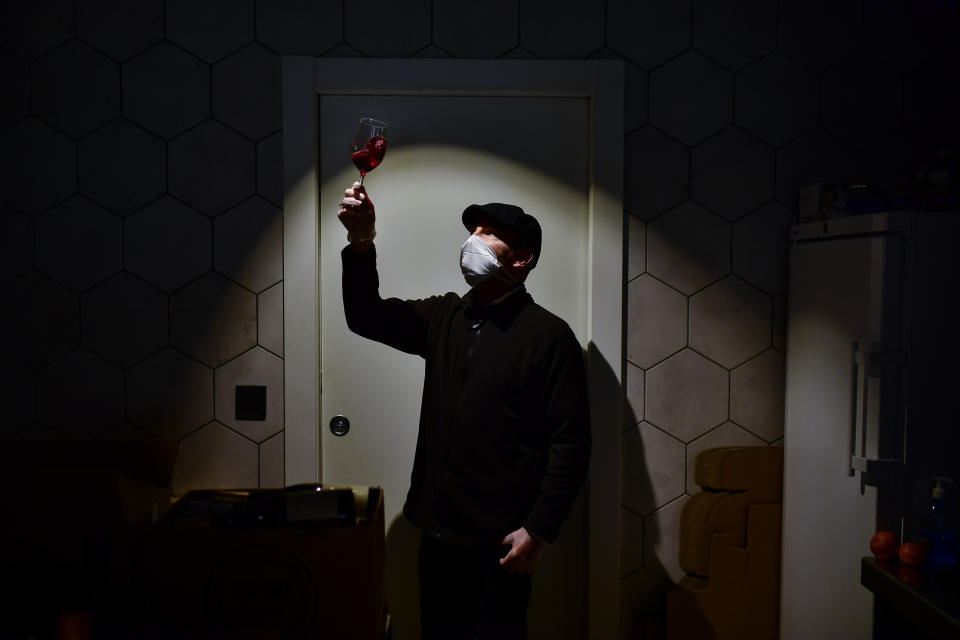 In this Wednesday, April 15, 2020 photo, Javier Flamarique poses for a photograph at his wine store in Pamplona, northern Spain. As Spain hunkers down after five weeks of home confinement, there are the brave few who keep the country going during a coronavirus outbreak that has killed over 20,000 of their fellow citizens. These laborers_ butchers, taxi drivers, pharmacists_ in the northern city of Pamplona as well as the rest of Spain's cities and towns are unified by their courage and one piece of equipment: the face mask. (AP Photo/Alvaro Barrientos)