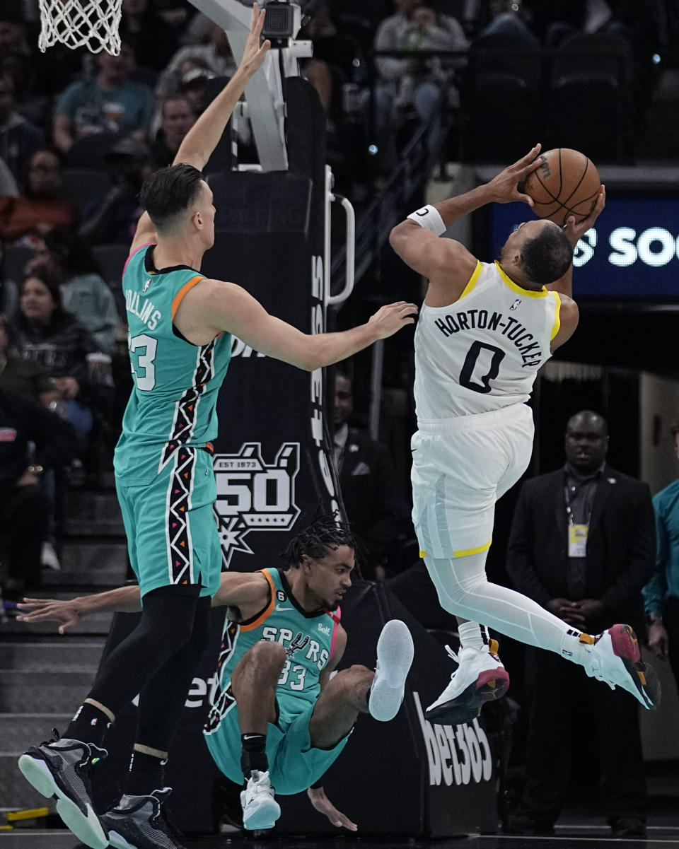 Utah Jazz guard Talen Horton-Tucker (0) drives to the basket against San Antonio Spurs forward Zach Collins, left, and guard Tre Jones during the first half of an NBA basketball game in San Antonio, Wednesday, March 29, 2023. (AP Photo/Eric Gay)
