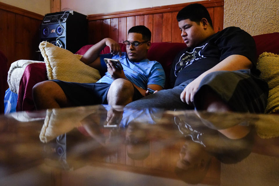 Mino Zuniga Gonzales, 19, left, and his brother Erick Zuniga Gonzales, 17, look at a smart phone in the Kensington section of Philadelphia, Sunday, May 16, 2021. The brothers are trying to rebuild their lives together with their mother Keldy Mabel Gonzales Brebe, a 37-year-old Honduran immigrant, after they were separated under a former "zero-tolerance" policy to criminally prosecute adults who entered the country illegally. (AP Photo/Matt Rourke)