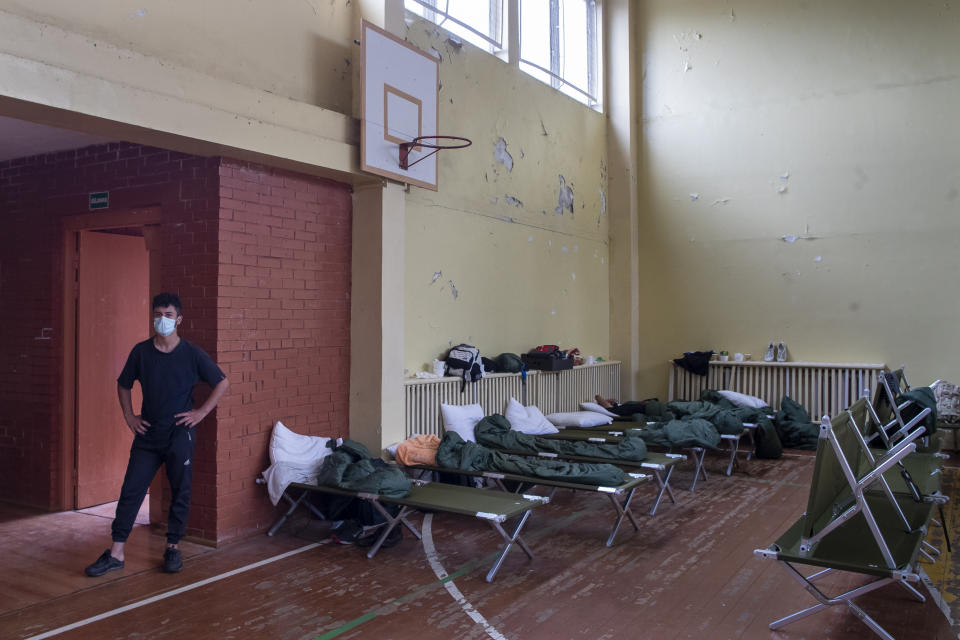 A migrant from Iraq stands in a sport hall where refugees live in a school building at the refugee camp in the village of Verebiejai, some 145km (99,1 miles) south from Vilnius, Lithuania, Sunday, July 11, 2021. Lithuania has struggled with a flow of migrants from the Middle East and Africa, a huge influx that officials in the tiny Baltic country say was organized by Belarusian authorities as part of a "hybrid war" against the European Union. (AP Photo/Mindaugas Kulbis)