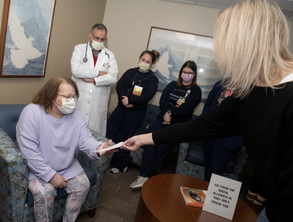 Rebecca Schneider, a Kent police and fire dispatcher, hands an envelope containing a check to Debra Holloway at UH Portage Medical Center's Seidman Cancer Center on Wednesday. The Kent Police Department started an initiative more than 12 years ago to raise money for local cancer patients.