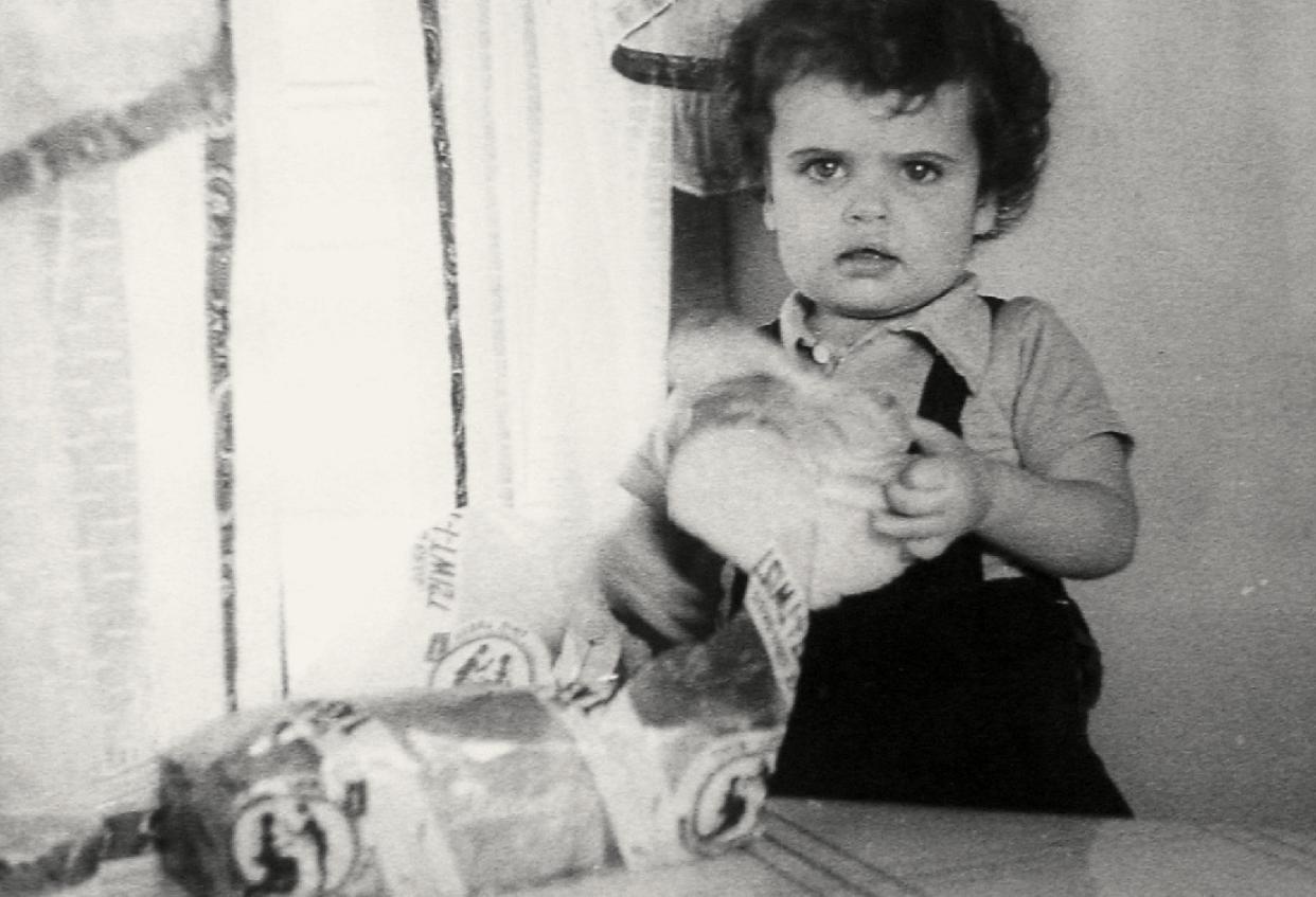 An archival photo of a little girl holding a piece of DeIorio's sliced Italian "Tasty Twist" bread.