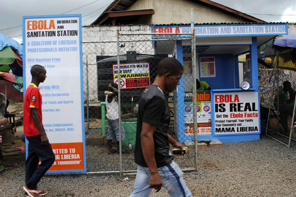 Pedestrians walk by an Ebola virus information and hand sanitizing kiosk in Monrovia, Liberia, October 4, 2014. Picture taken October 4, 2014. REUTERS/James Giahyue (LIBERIA - Tags: HEALTH DISASTER SOCIETY)