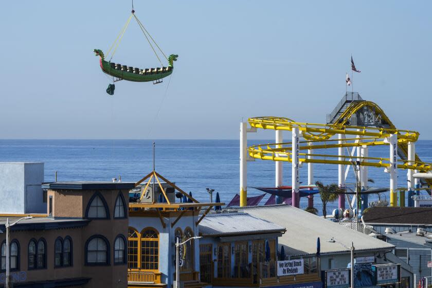 The Sea Dragon, a retired swinging ship ride at Pacific Park on the Santa Monica Pier, is lifted up by a helicopter in Santa Monica, Calif., Thursday, March 9, 2023. The ride is transported to its retirement home in Ventura County, Calif., after carrying more than 12 million guests for nearly 30 years, according to the amusement park. (AP Photo/Jae C. Hong)
