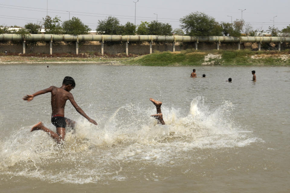 Children cool themselves in a lake as the temperature rises in New Delhi, India, Monday, May 27, 2024. (AP Photo/Manish Swarup)